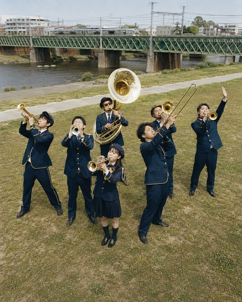 河川敷で管楽器を掲げる7人組ブラスバンド